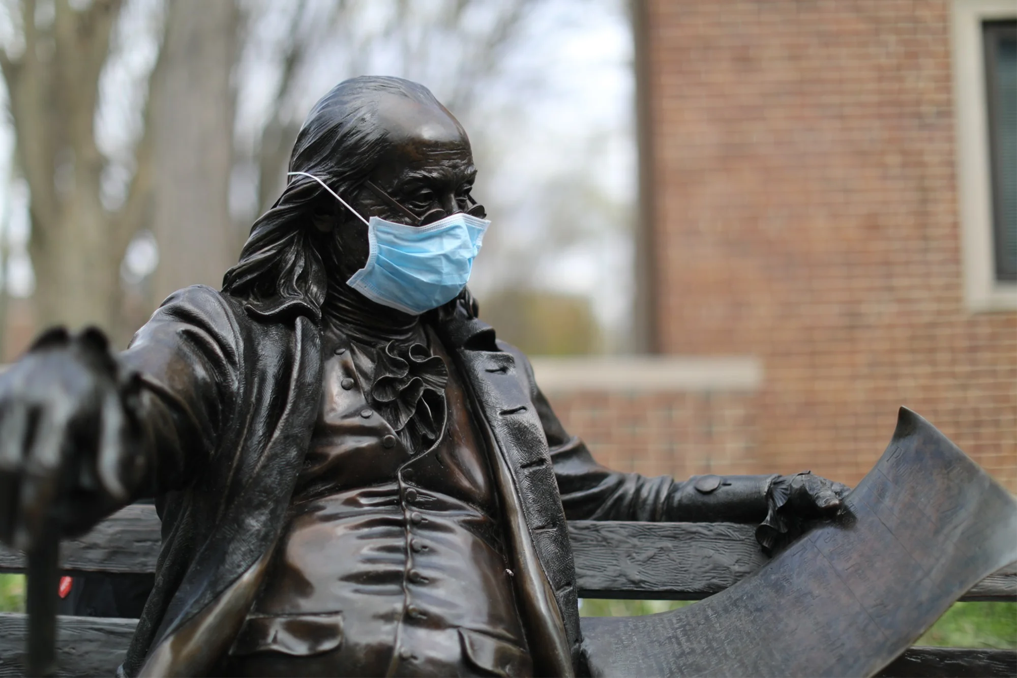 Benjamin Franklin — “An ounce of prevention is worth a pound of cure” Bronze statue of Benjamin Franklin seated on a bench, wearing a surgical mask